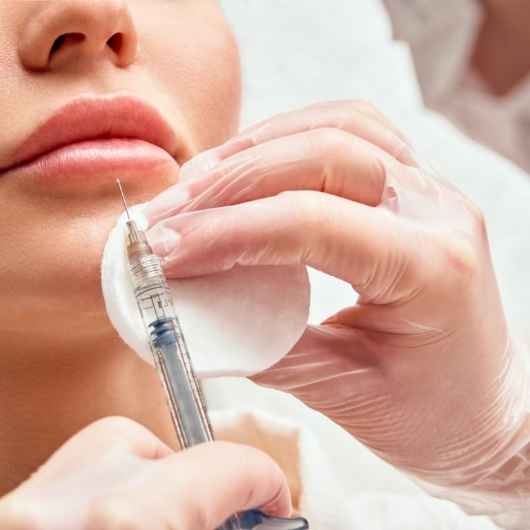 lip shape correction procedure in a cosmetology salon. The specialist makes an injection on the lips of the patient. Lip augmentation.